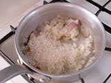 玉ねぎがしんなりしてきたら、ベーコン、米を加え、焦げないように弱火で炒める。